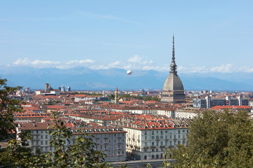 Fototapeta na wymiar Turin rooftops view, Mole Antonelliana tower and hot air balloon in a sunny summer day in Italy