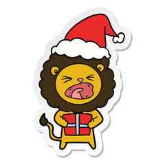 sticker cartoon of a lion with christmas present wearing santa hat