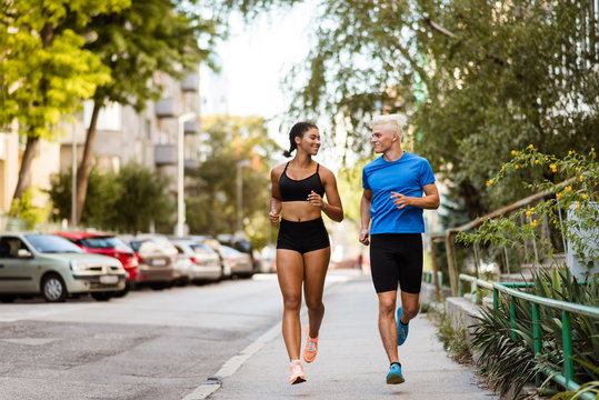 Active joggers training outdoors on sidewalk