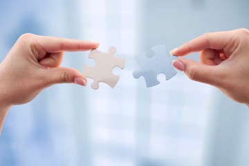 Human hands joining puzzle parts on background