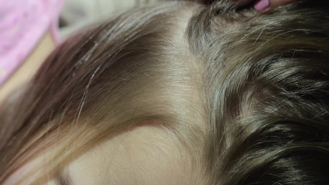 Mom cleans her daughter's hair from nits and lice with a special comb, combs insects from the head. Concept children's head lice