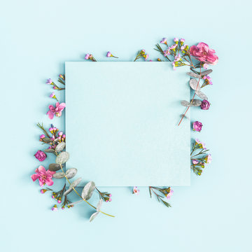 Flowers composition. Paper blank, pink flowers on pastel blue background. Flat lay, top view, copy space, square