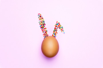 Minimal concept Easter. Egg with rabbit ears of sweets on colored background. Сreative design concept