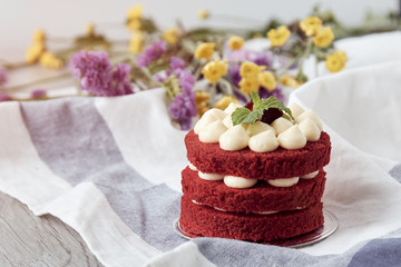 Sweet brown cake with berry on top placing with pink flower as decorated item on the wooden table