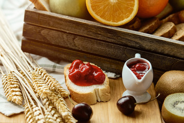 Many kind of sweet fruit, jam, and bread placing together on wooden board near window