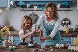 Mother and daughter coloring eggs at home