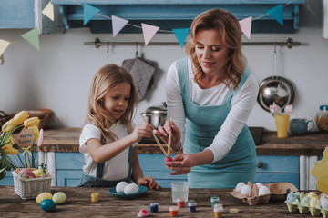 Mother and daughter coloring eggs at home