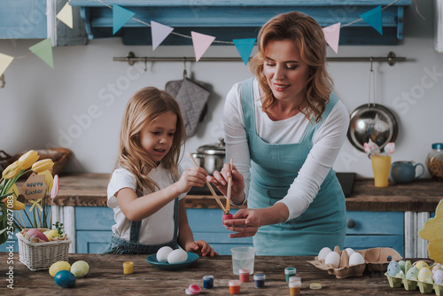 Mother and daughter coloring eggs at home