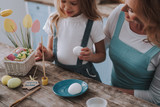 Smiling child coloring eggs together with mom