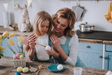 Happy mom embracing daughter while coloring eggs