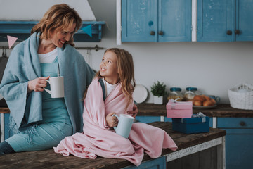 Mom and daughter with drink on kitchen