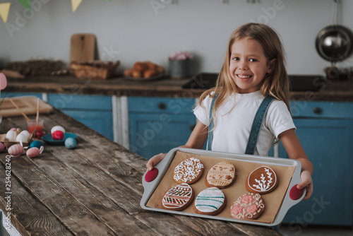 Little girl showing egg shaped cookies on pan