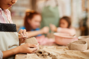 Obraz na płótnie Canvas Closeup of unrecognizable little girl shaping clay in pottery class for children, copy space