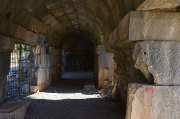 Fototapeta na wymiar Path through a dark curved arched tunnel in old stone ruins