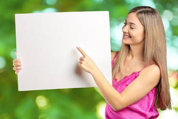 Happy smiling beautiful young woman in pink smart casual clothing showing blank signboard or copyspace for slogan or text