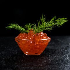 Red caviar in  bowl, dark background