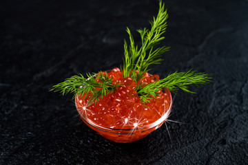 Red Caviar in bowl over black background