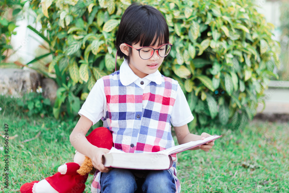 Poster Cute little girl with glasses reading book