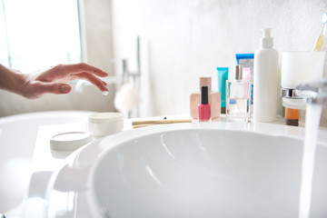 Young lady taking drop of face cream on finger