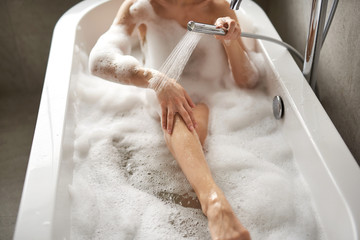 Obraz na płótnie Canvas Young lady showering herself taking foam bath