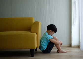 Child autism sitting beside sofa.