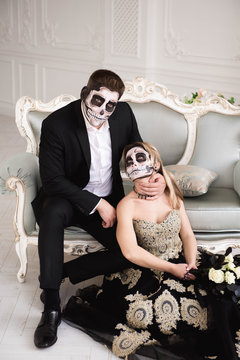 Couple with dark skull makeup on white background. Halloween