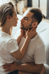 Young romantic couple is kissing and enjoying the company of each other at home