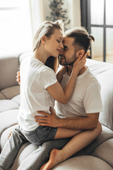 Fototapeta na wymiar Young romantic couple is kissing and enjoying the company of each other at home