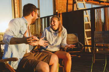 Young couple sitting on the porch and laughing during the sunset