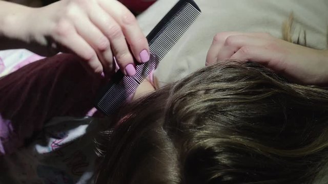Mom cleans her daughter's hair from nits and lice with a special comb, combs insects from the head. Concept children's head lice