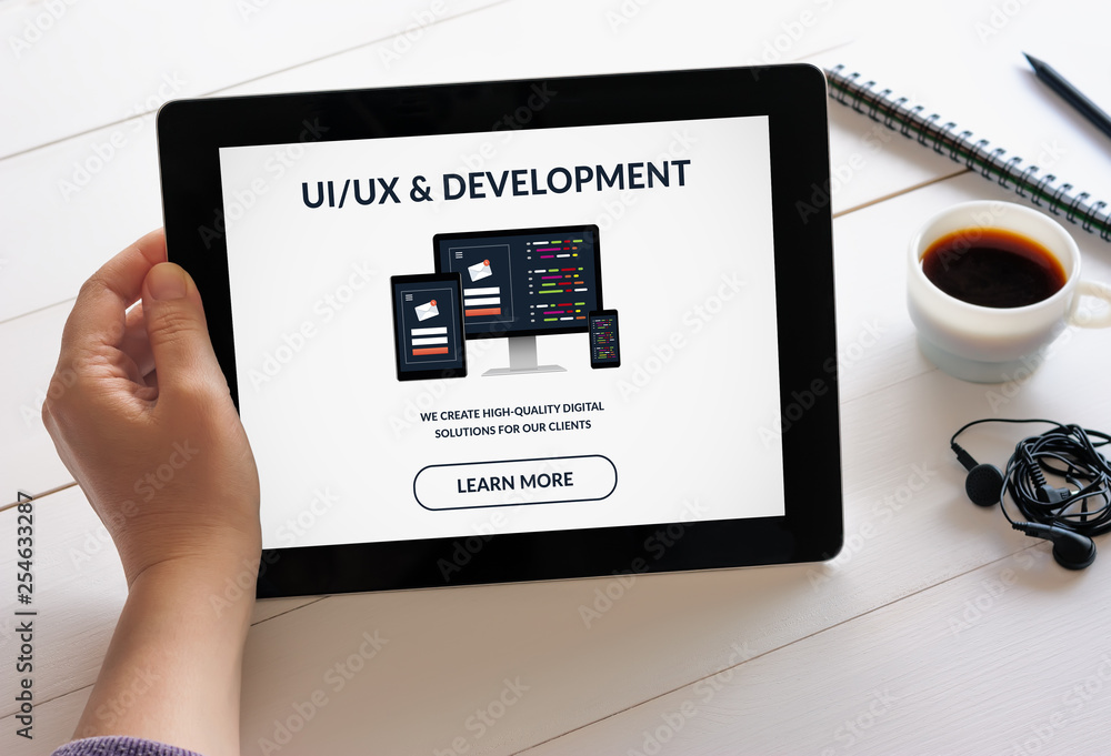 Wall mural hand holding tablet with ui/ux design and development concept on screen