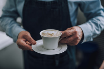 Old man demonstrating drink with beautiful latte art