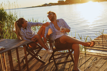 Young woman and man using smartphone and laughing by the river