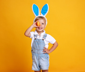 funny happy child boy with easter eggs and bunny ears on yellow