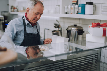 Obraz na płótnie Canvas Senior man in apron preparing delicious pastries for special order