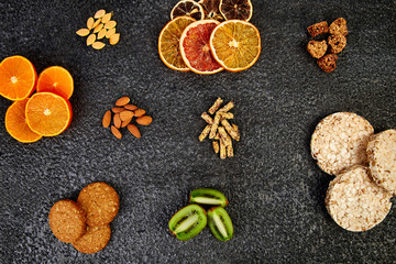 Fototapeta na wymiar Healthy snacks - variety oat granola bar, rice crips, almond, kiwi, dried orange