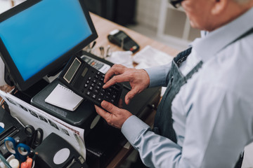 Male entrepreneur using calculator and working at cash desk