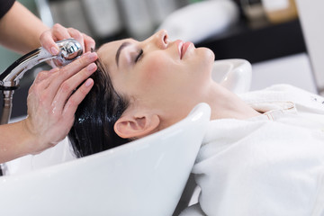 Side view of lady enjoying of hair procedure by stylist in saloon