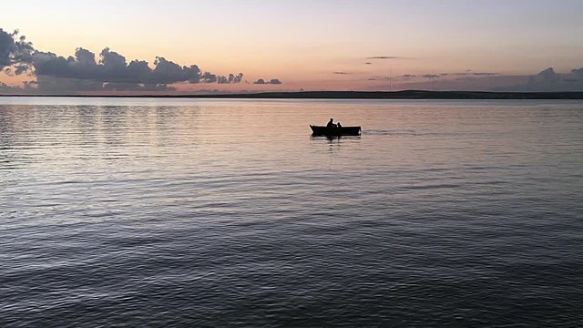 Father and son in a rowboat. Silhouettes of two people boating at sunset.