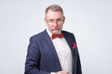 Senior european man in blue suit and glasses looking at camera