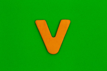 Letter v made of wood painted orange on green background
