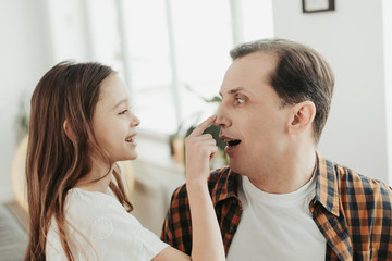 Happy girl having fun and touching nose of her father