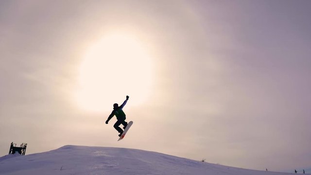 Silhouette of snowboarder jumping on mountain ski slope.