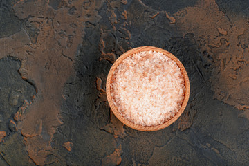 Pink himalayan salt in wooden bowl on black background
