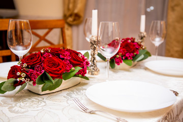 2 floral arrangements of red roses and carnations for table decoration (wedding, restaurant) on a server table, table setting