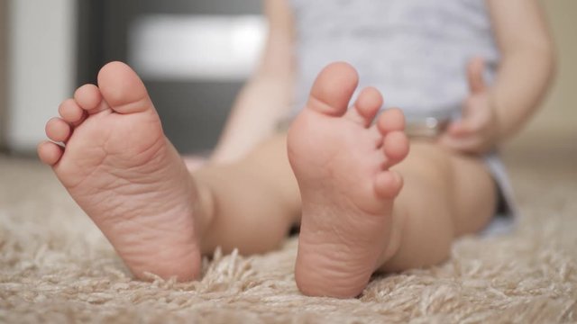 Baby foot at white carpet, close up.