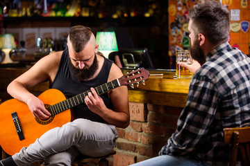 Friends relaxing in bar or pub. Hipster brutal bearded spend leisure with friend in bar. Real men leisure. Cheerful friends relax with guitar music. Man play guitar in bar. Friday relaxation in bar