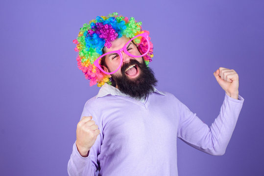 Having fun. Holiday fun and carnival concept. Man bearded wear colorful wig and funny glasses on violet background. Clown and circus. Party fun. Enjoy being crazy. Feel free to express yourself