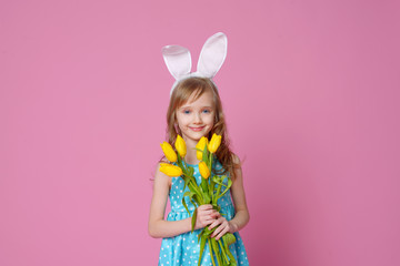 Obraz na płótnie Canvas Cute little girl in the form of an Easter Bunny with a bouquet of yellow tulips. concept of holidays, fashion and beauty. Happy Easter! Selective focus.
