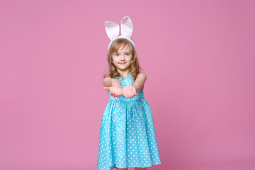 Obraz na płótnie Canvas Cute little blonde girl in the shape of an Easter Bunny and a blue dress with a pea pattern. Concept of the celebration, advertising and fashion. happy Easter. Selective focus.